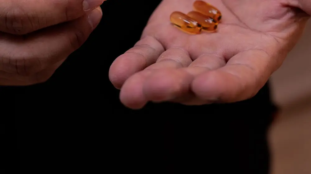 Hand holding natural testosterone support supplement capsules